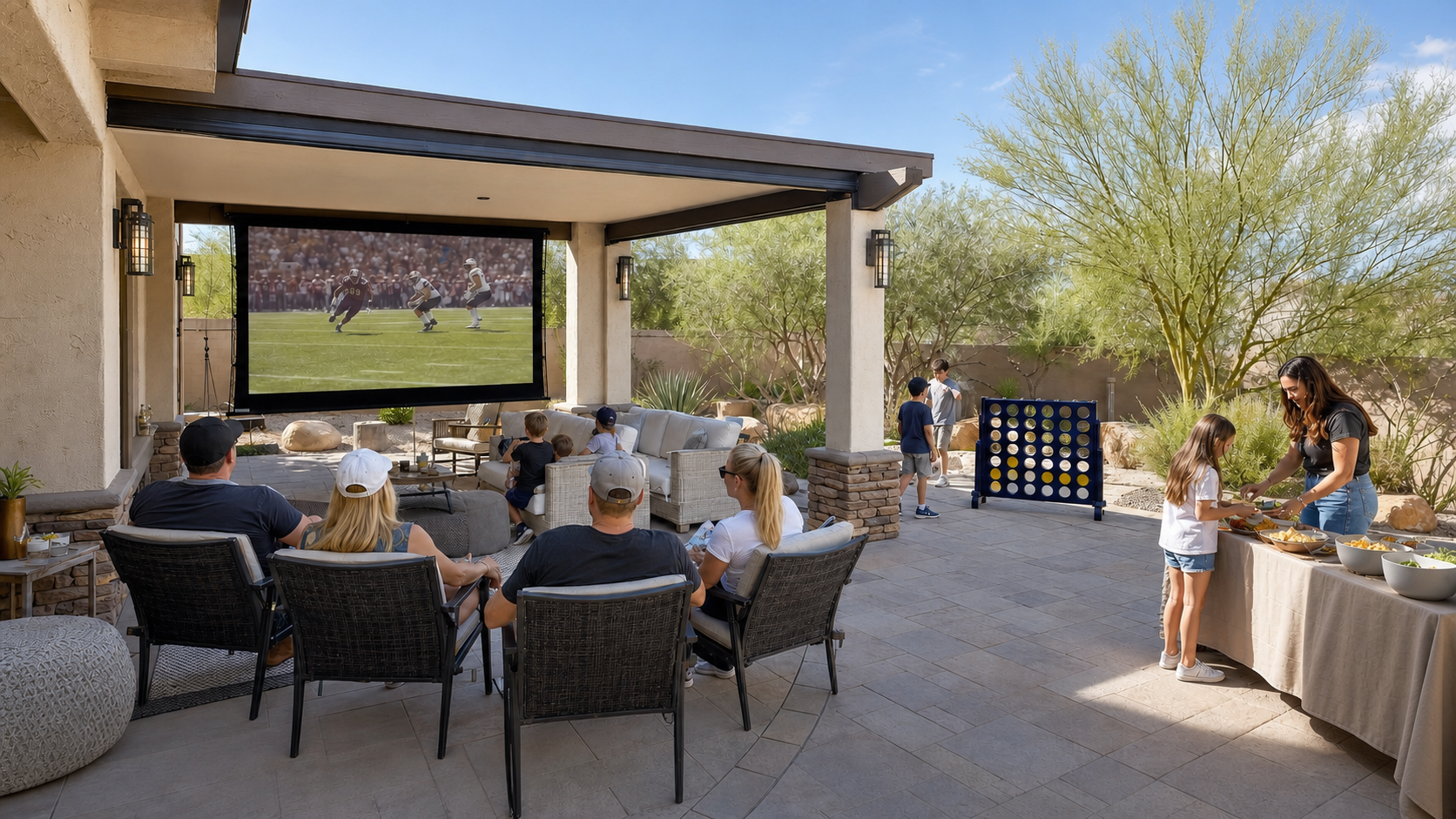 Friends and families watching football beside a self-serve snack table and giant Connect 4 in a bright East Valley Arizona backyard