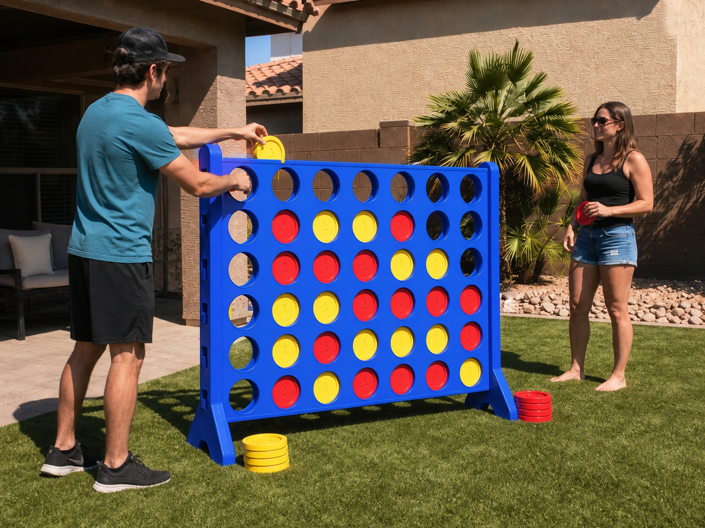 Two adults playing Giant Connect 4 on a sunny Arizona backyard lawn