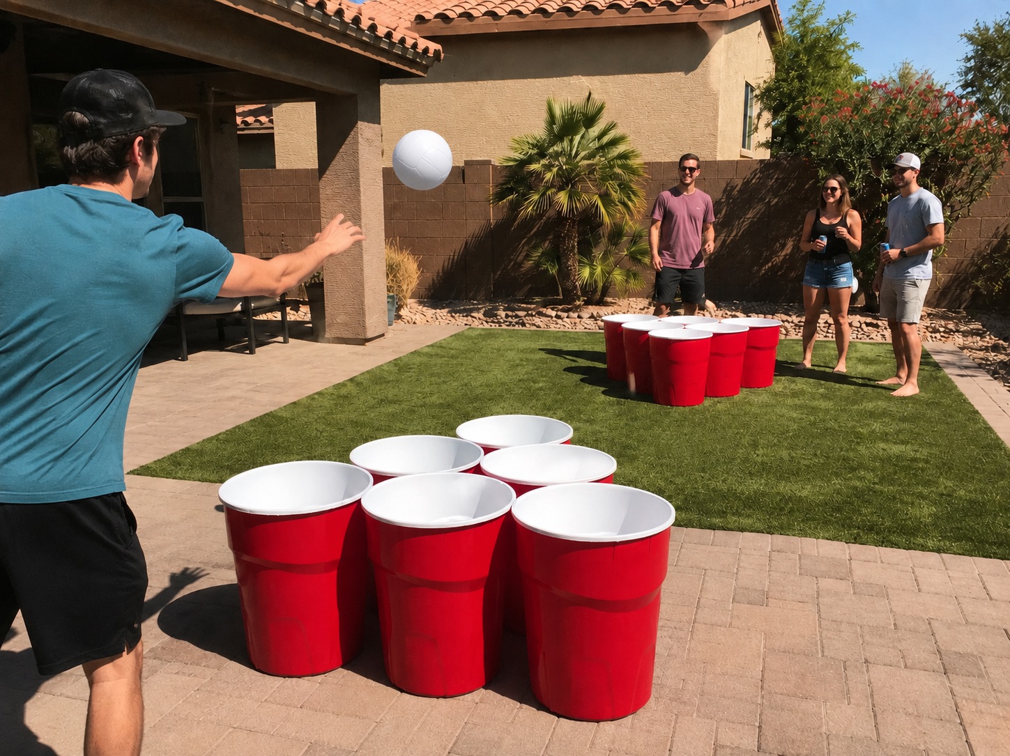 Guests playing Giant Yard Pong with oversized red cups and a white ball in an Arizona backyard