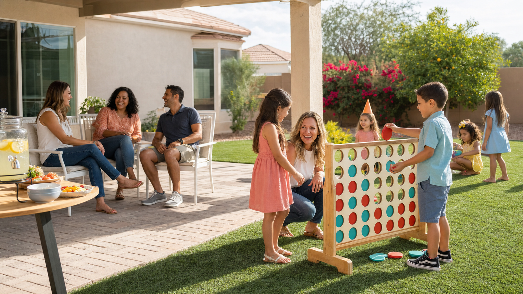 Kids and adults enjoying a shared birthday party with giant Connect 4, white seating, and a snack table in a bright East Valley Arizona backyard